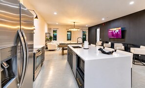 A modern kitchen with a central island, stainless steel appliances, and a flat-screen TV mounted on the wall. - 14 Beds Walk 2 Broadway Hot Tub Pool Sauna Firepit (Nashville)