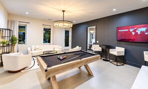 A modern living room with a pool table, white sofas, and a large flat-screen TV mounted on the wall. - 14 Beds Walk 2 Broadway Hot Tub Pool Sauna Firepit (Nashville)