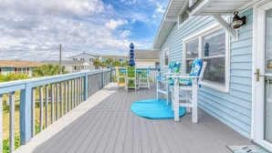 A covered deck with outdoor furniture, a view of the ocean, and a house in the background. - Carolina Palms - 5 Bedroom Second Row Beach House (Garden City Beach)