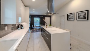 A modern kitchen with a central island, built-in appliances, and a view to a dining area. - Modern Retreat | Heated Pool, Jacuzzi & Near Beach (Naples)