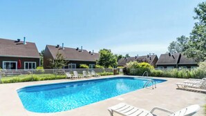 A rectangular swimming pool with clear blue water, surrounded by lounge chairs and a paved deck. - Le Valmont | Townhouse 🌾 (Beaupré)