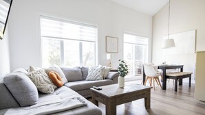 A modern living room with a sectional sofa, a coffee table, and a dining area with a table and chairs. - Le Valmont | Townhouse 🌾 (Beaupré)