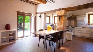 A spacious kitchen with a central island, wooden beams, and a view through a glass door. - Villa Gelso: your luxury villa with pool and sauna in Le Marche region (Provincia di)