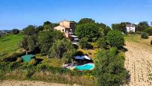A hillside property with a swimming pool, a large house, and surrounding greenery. - Villa Gelso: your luxury villa with pool and sauna in Le Marche region (Provincia di)