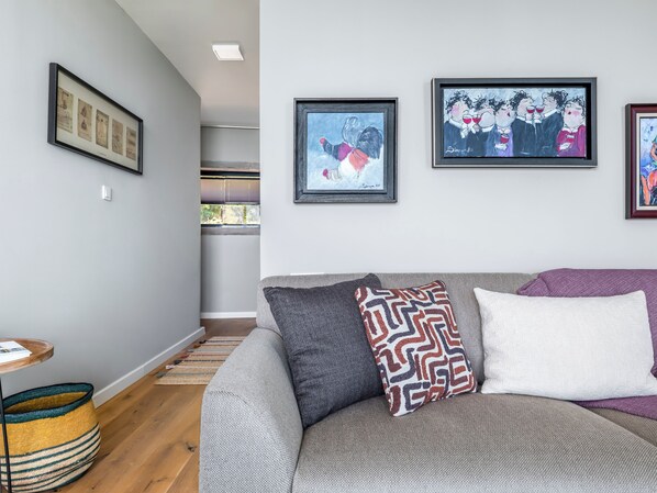 A modern living room with a grey sofa, patterned cushions, and framed artwork on the wall. - Rust House (Ayvacik)