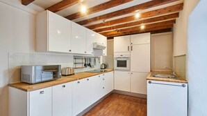 Una cocina compacta con armarios blancos, una encimera de madera y un horno empotrado.