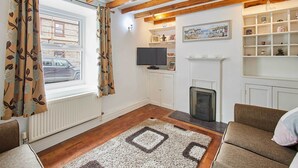 Una sala de estar con chimenea, televisión y estantería.