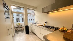 Een moderne keuken met een groot raam, een gasfornuis en een houten aanrecht.
