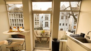 Een kleine keuken met een eethoek, een radiator en stadszicht door grote ramen.