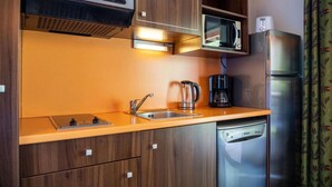 A compact kitchen with a microwave, coffee maker, and a dishwasher. - 1st floor, swimming pool, hammam, terrace, parking, tv, 27m², Pra Loup (Jausiers)