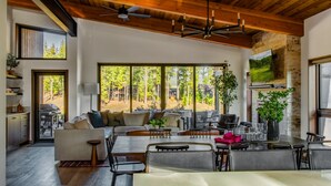 A spacious living area with a high ceiling, large windows, a dining table, and a cozy seating arrangement. - 5 King Beds on Golf Course with a VIEW 0.6 mile walk to Winery! (Cle Elum)