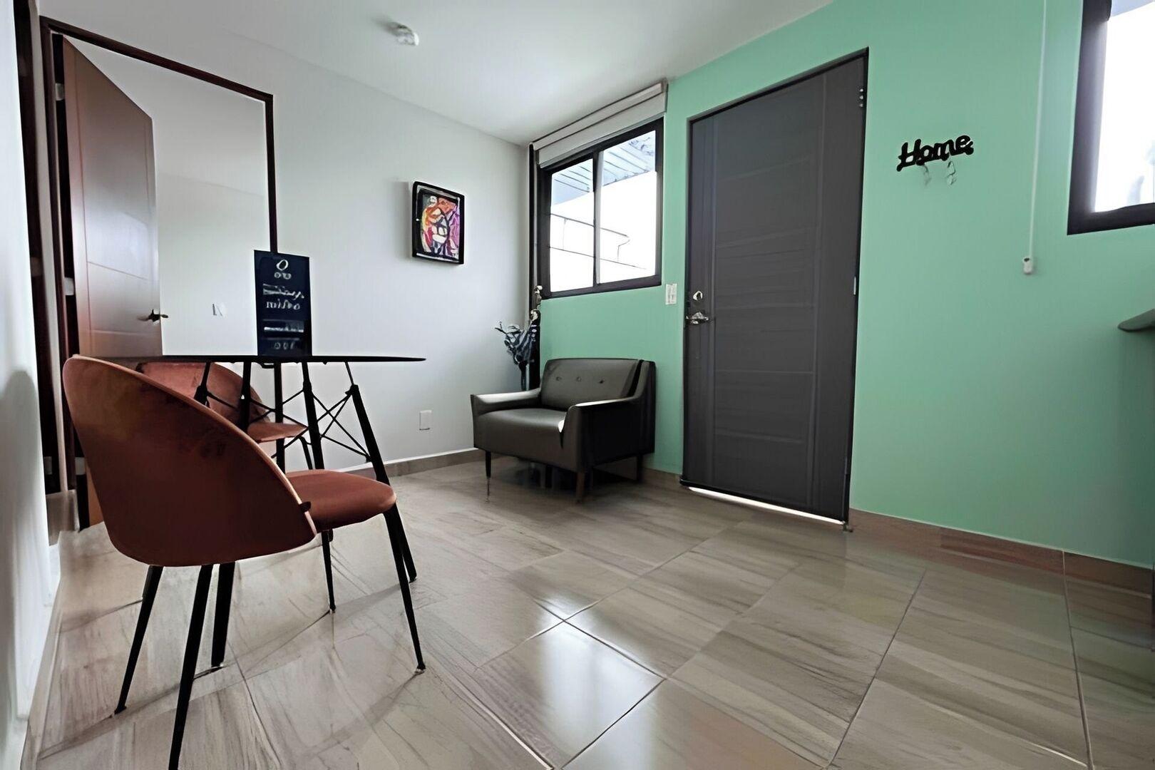 A room with a dining table, chairs, a sofa, a door, and a window.