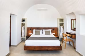 A bedroom with a large bed, wooden headboard, bedside tables, a chair, and a wardrobe.