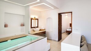 A modern bathroom with a glass-enclosed bathtub, a large mirror, and a white vanity. - Santorini Luxury Suite w/ Rooftop HotTub & SeaView (Akrotiri, Santorini)
