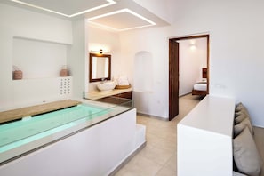 Casa de banho moderna com banheira de hidromassagem envidraçada, um espelho grande e toucador branco.