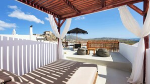A sunlit outdoor seating area with a view of the landscape. - Santorini Luxury Suite w/ Rooftop HotTub & SeaView (Akrotiri, Santorini)
