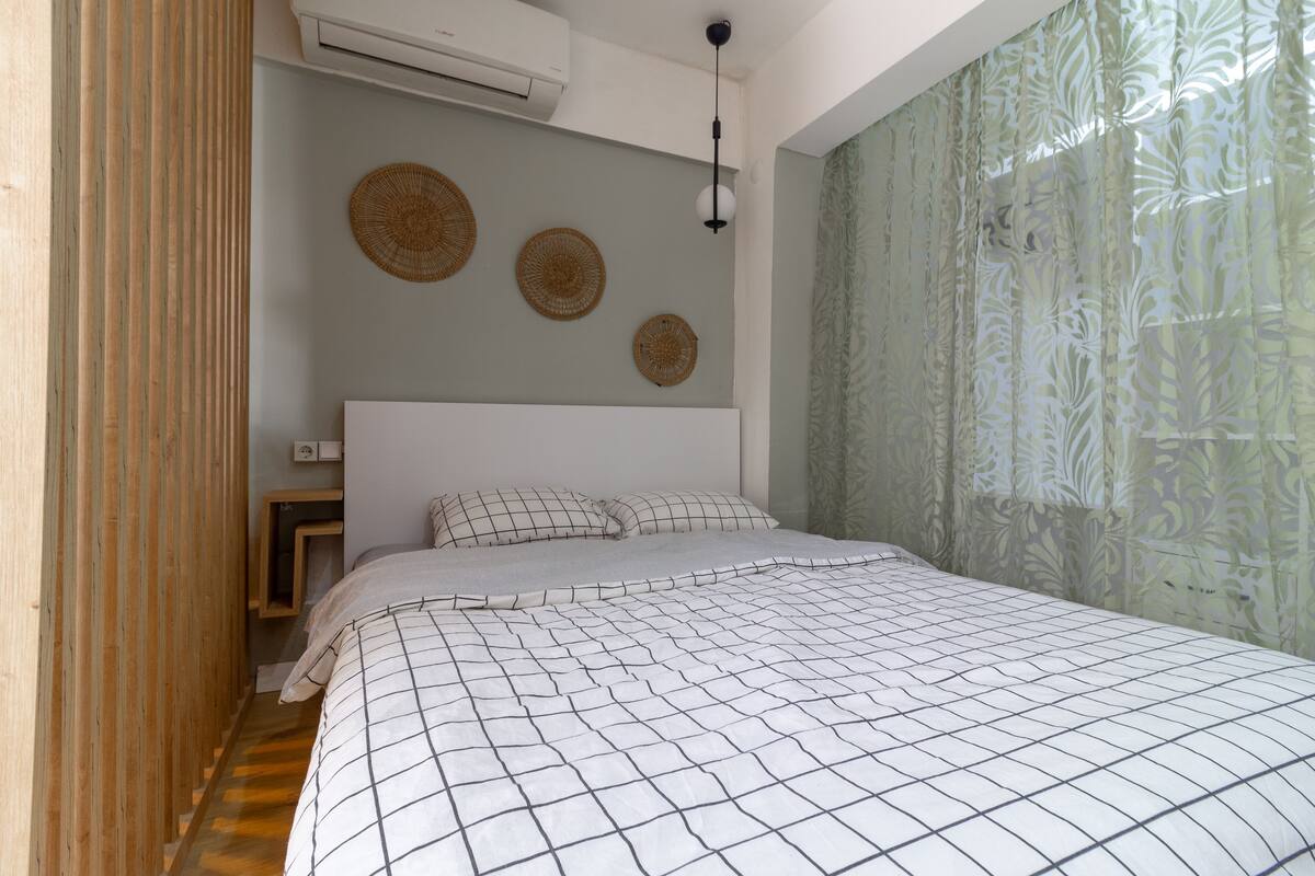Un dormitorio con cama, aire acondicionado de pared y lámpara en el techo.