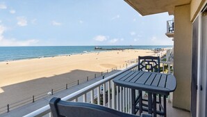 Un balcon donnant sur une plage, avec une table et une chaise.