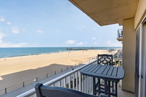 A balcony with a view of a beach, a table, and a chair. - Wake Up Hearing The Waves |Beach Front Haven 403 (Virginia Beach)