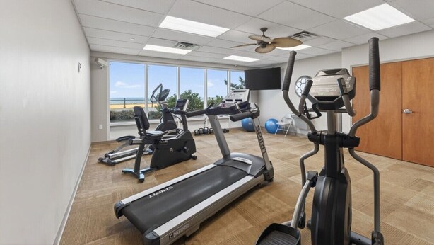 Une salle de sport équipée de tapis de course, de vélos elliptiques et d’un vélo d’appartement.