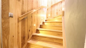 Una scala in legno con corrimano e lampade a parete.
