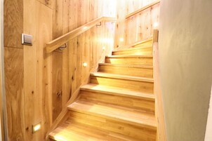 Una escalera de madera con barandilla e iluminación en la pared.
