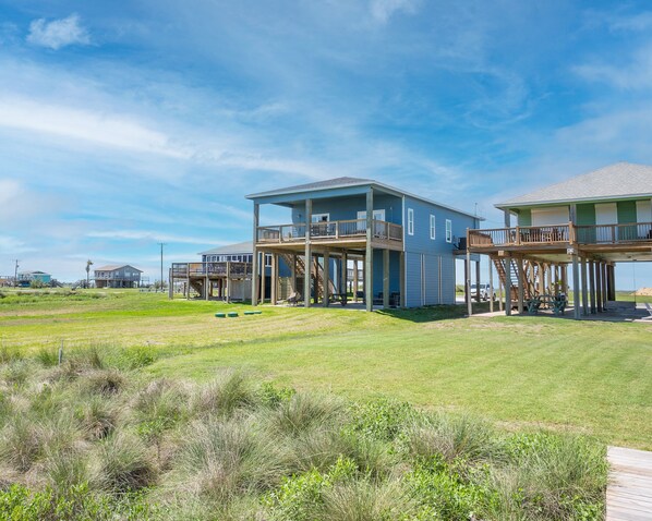 A beachfront property with multiple levels, outdoor seating, and a clear view of the ocean. - Beautiful Beachfront Home with Beach Access. (Sargent)