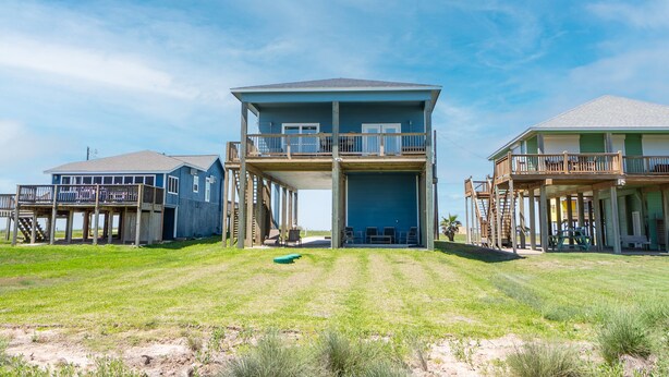 A beachfront property with a central building featuring a balcony and a covered area. - Beautiful Beachfront Home with Beach Access. (Sargent)