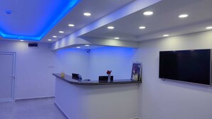 Un área de recepción con un mostrador curvo, un televisor de pantalla plana e iluminación empotrada en el techo.