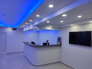A reception area with a curved counter, a flat-screen TV, and recessed ceiling lighting.