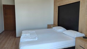 Un dormitorio con cama, cabecera de madera, mesita de noche y armario de madera.
