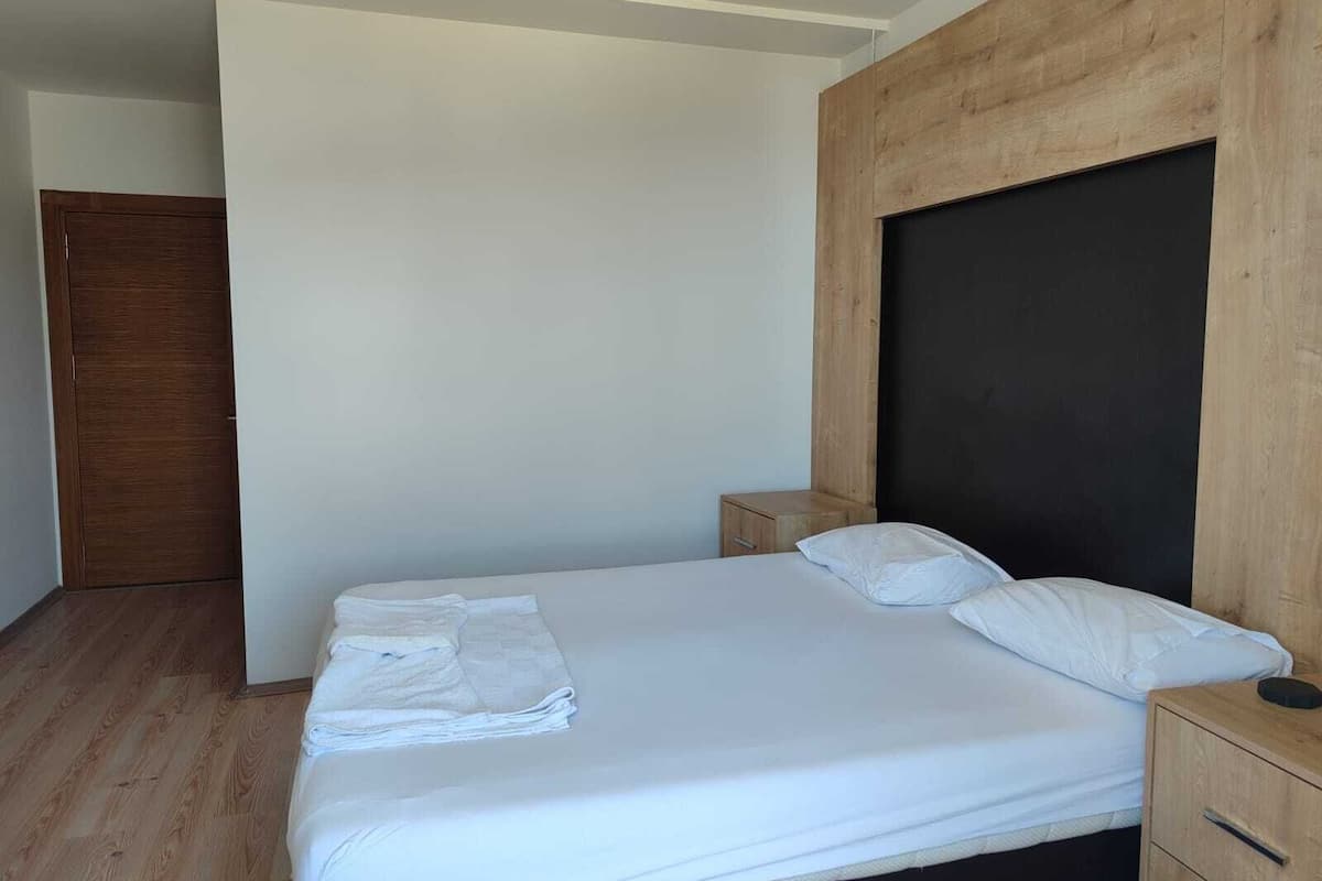 A bedroom with a bed, wooden headboard, a nightstand, and a wooden wardrobe.