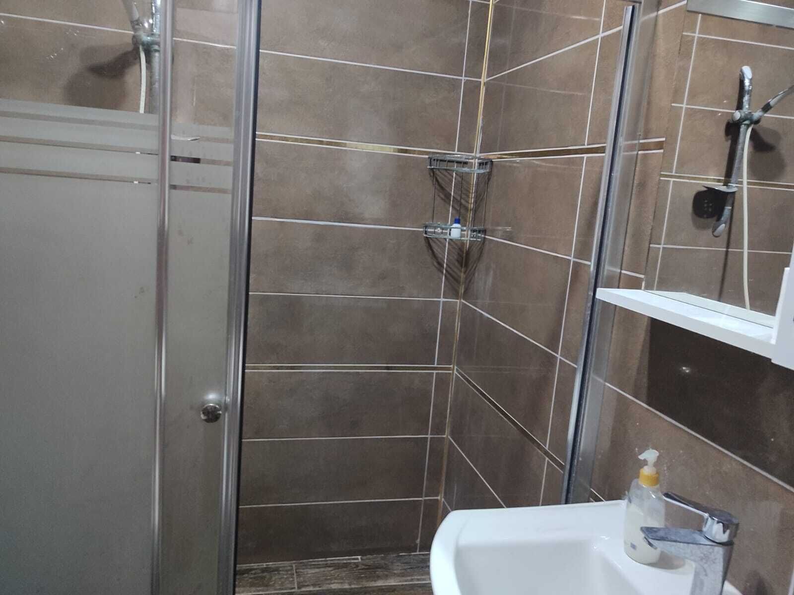 Une salle de bain avec une douche, un lavabo et un miroir.