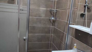 Une salle de bain avec une douche, un lavabo et un miroir.