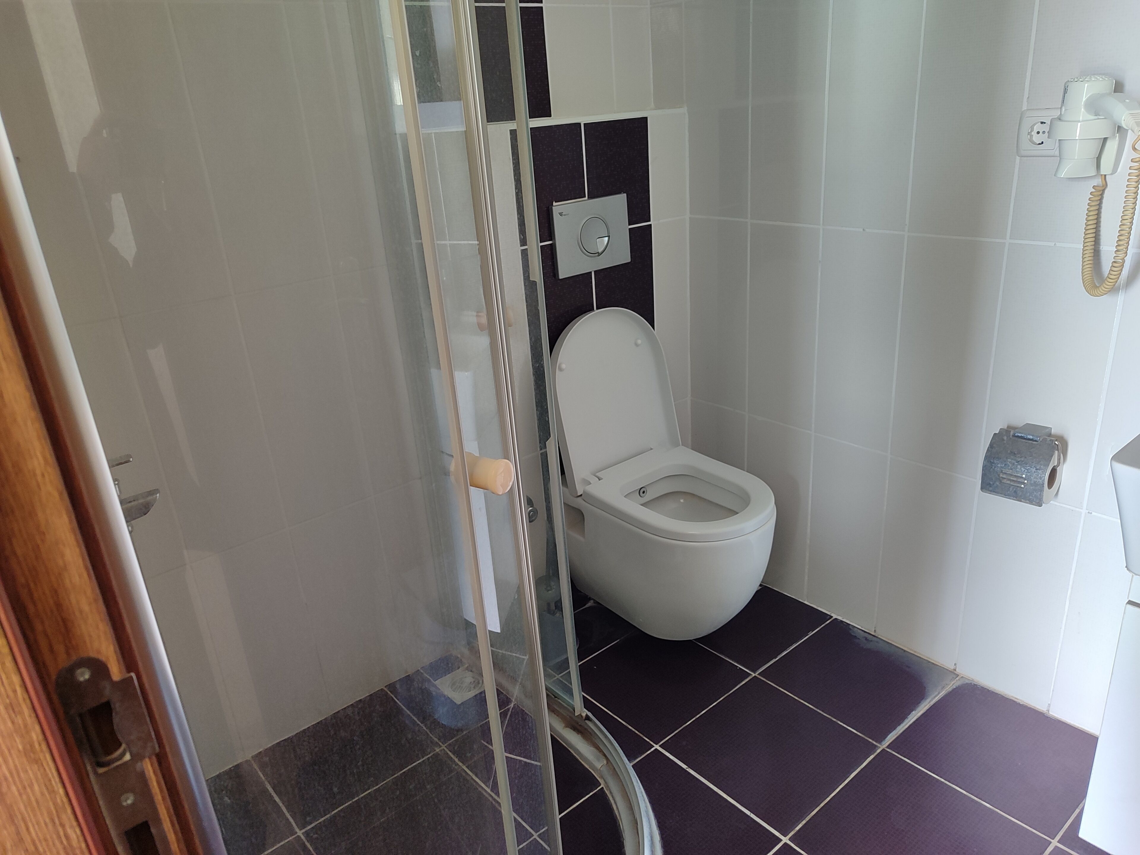 A bathroom with a toilet, a shower enclosure, and a towel rack.
