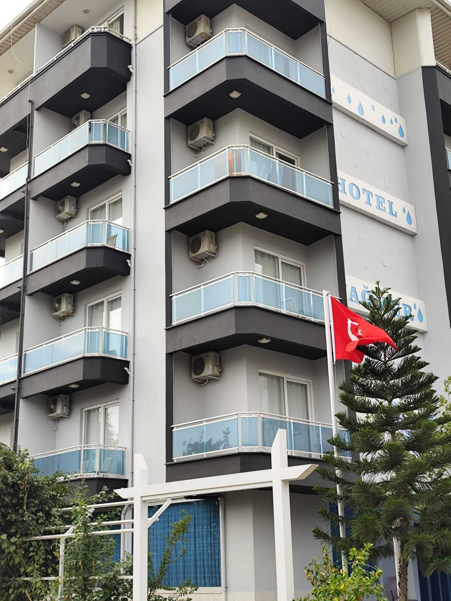 A multi-story hotel building with balconies, air conditioning units, and a flag.