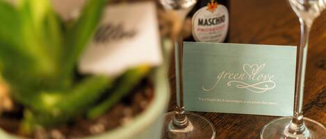 Una planta en maceta, una botella de vino Maschio y dos copas de vino con una tarjeta que dice 'green love'.