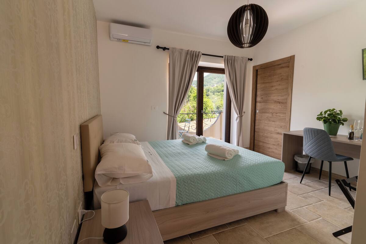 Un dormitorio con cama, escritorio, silla y planta en maceta.