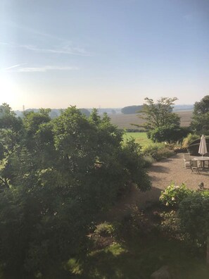 A view of a countryside landscape with a dirt path, trees, and a table with chairs and an umbrella. - Stunning Hall Cottage, near York and Leeds (Wighill)