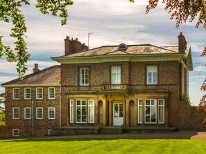 A two-story brick building with a symmetrical facade, multiple windows, and a central entrance with columns. - Stunning Hall Cottage, near York and Leeds (Wighill)
