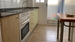 Eine Küche mit weißen Schränken, einer Arbeitsplatte aus Granit, einem eingebauten Backofen und einem Fenster mit Milchglas.