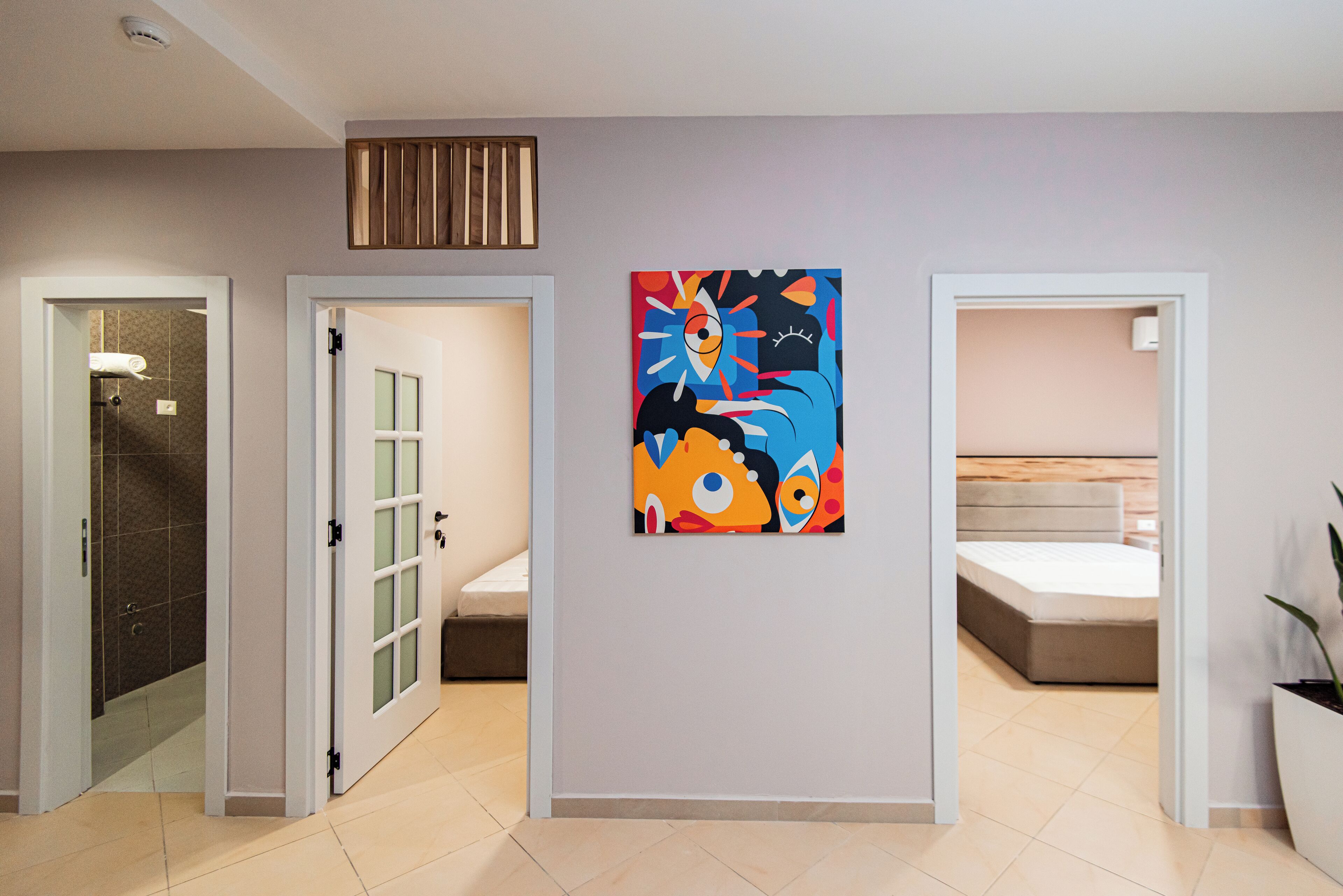 A hallway with a bed, a shower, and a painting on the wall.