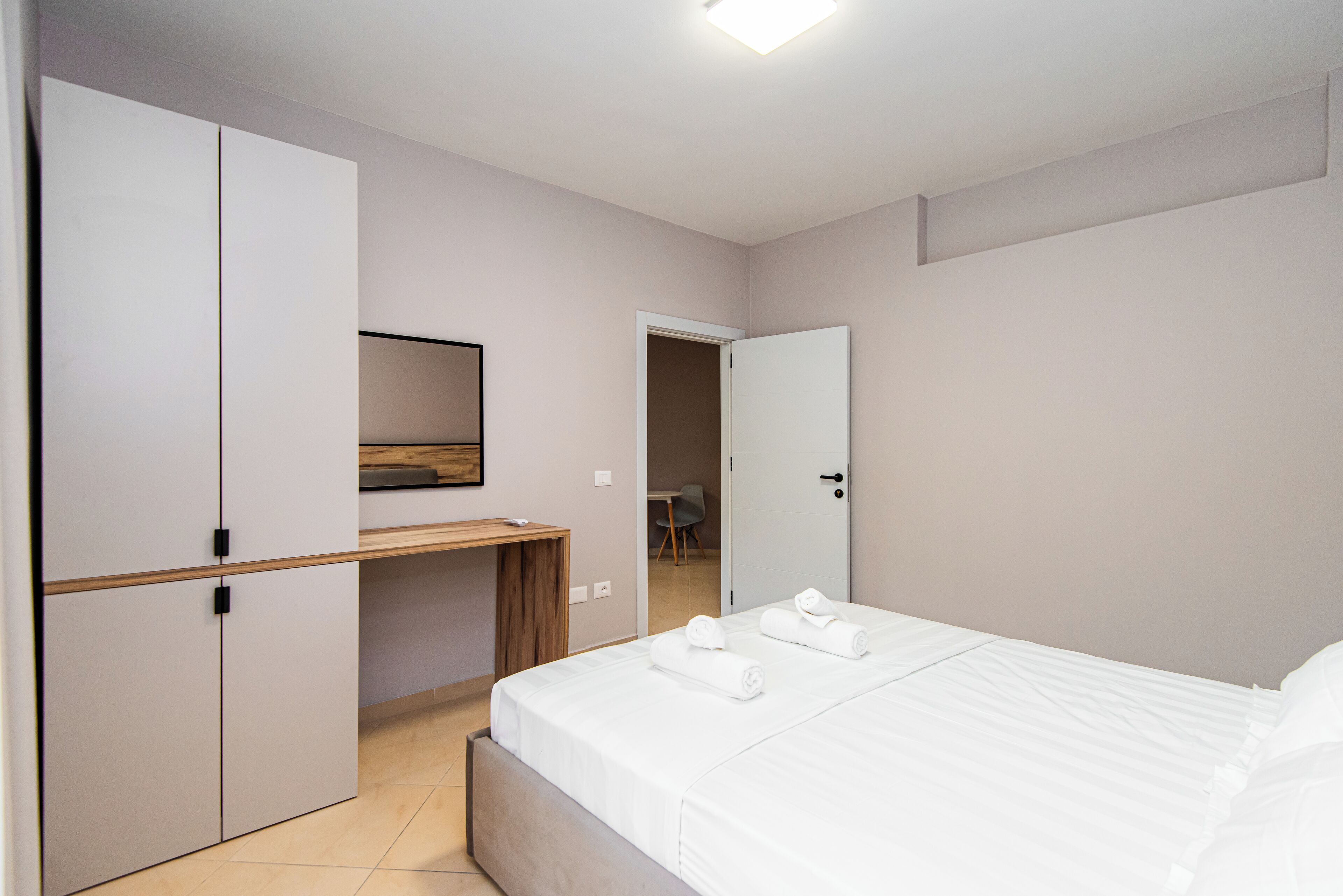 A bedroom with a bed, a desk, and a wardrobe.