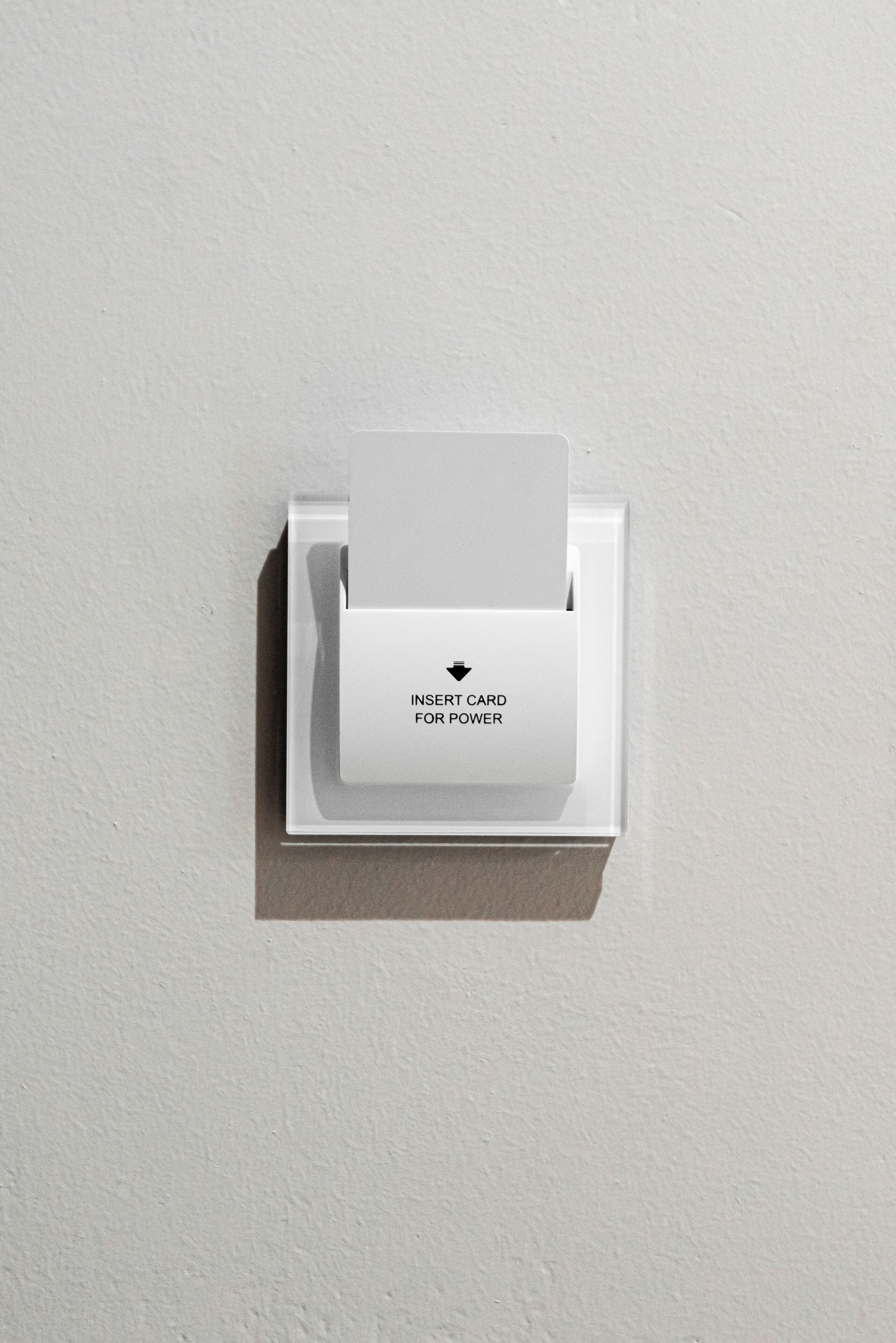 Un lector de tarjetas blanco montado en una pared con un letrero que dice 'INSERTAR TARJETA PARA ENERGÍA'.