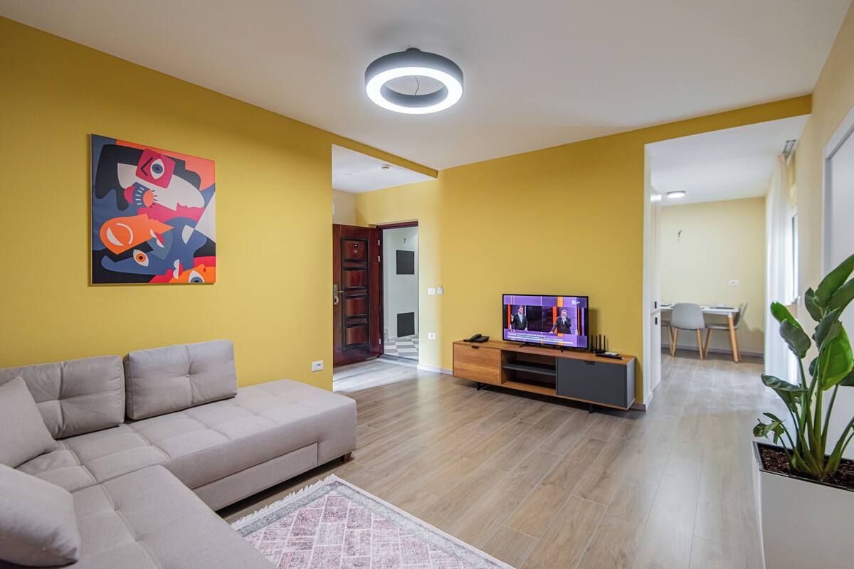 A modern living room with a sofa, TV, and artwork on the wall.