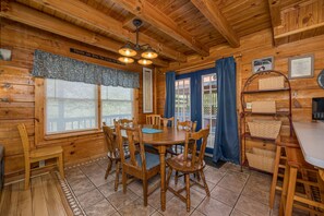A wooden interior with a dining table surrounded by chairs, a chandelier, and a window with curtains. - Easy Access*Mt. LeConte Views*Near Wedding Venue (GATLINBURG)