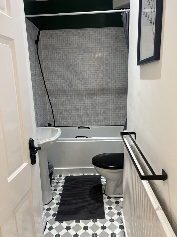 A small bathroom with a white sink, a bathtub, and a toilet.