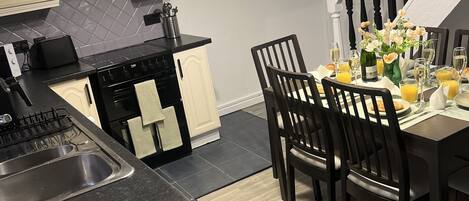 A modern kitchen with a black countertop, white cabinets, and a dining area with a table set for six.