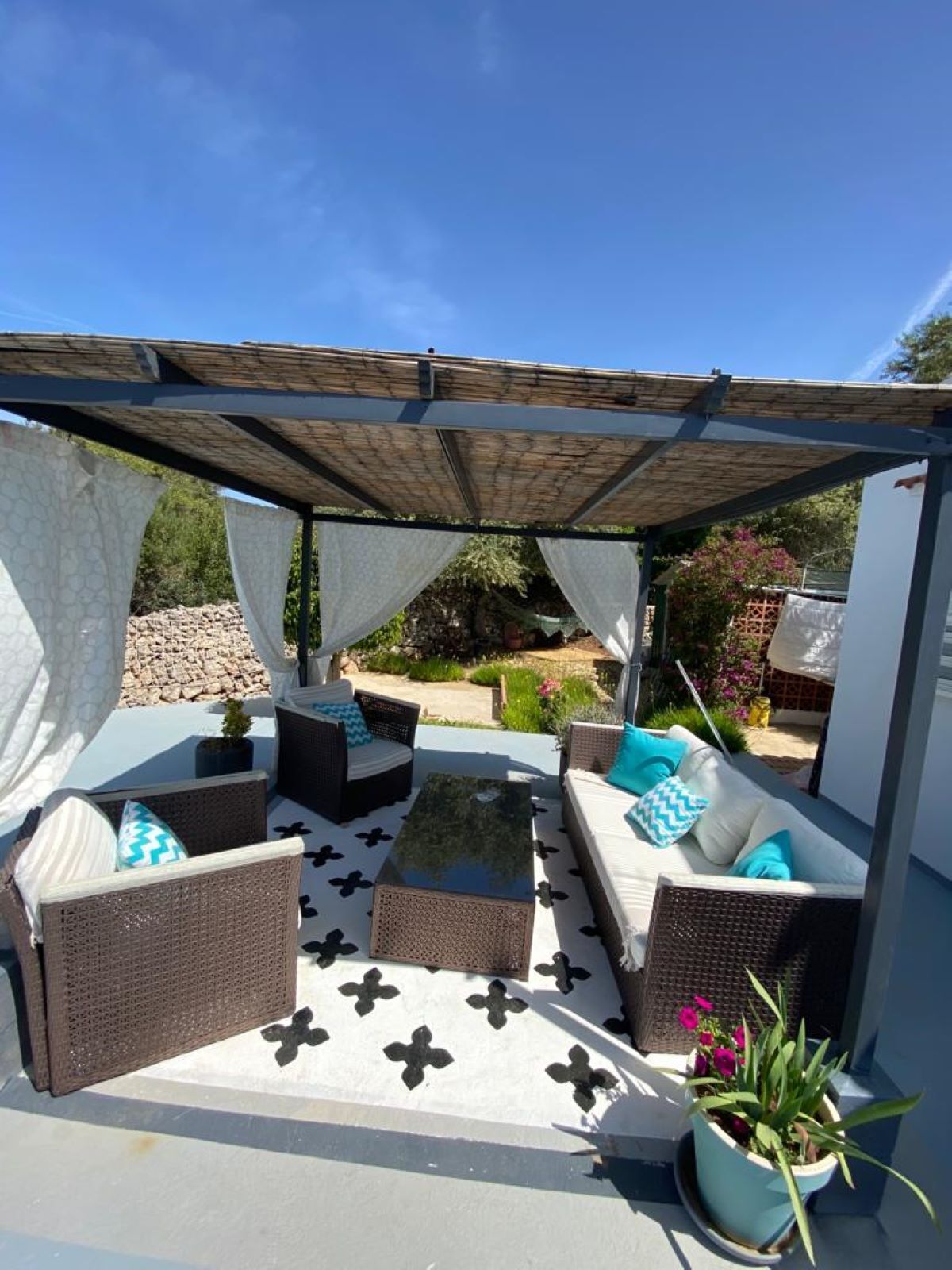 An outdoor patio with wicker furniture, a patterned floor, and a pergola.