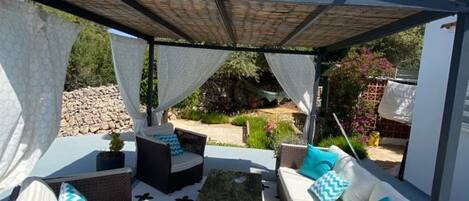 An outdoor patio with wicker furniture, a patterned floor, and a pergola.